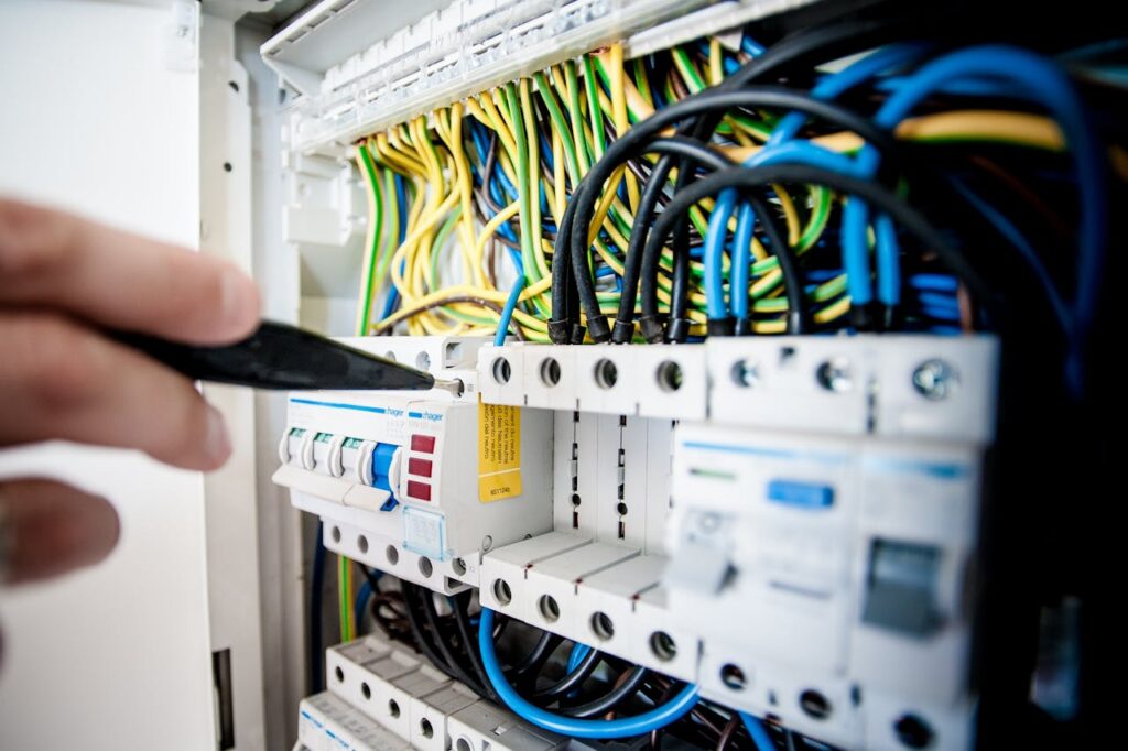 pexels photo 257736 Hand of electrician working on a circuit breaker panel with colorful wires, ensuring safe electrical connections.
