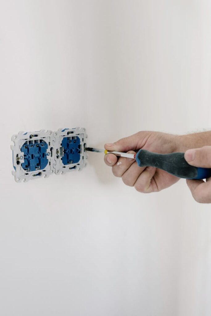 pexels photo 5691589 Close-up of hands using a screwdriver to install electrical sockets on a white wall.